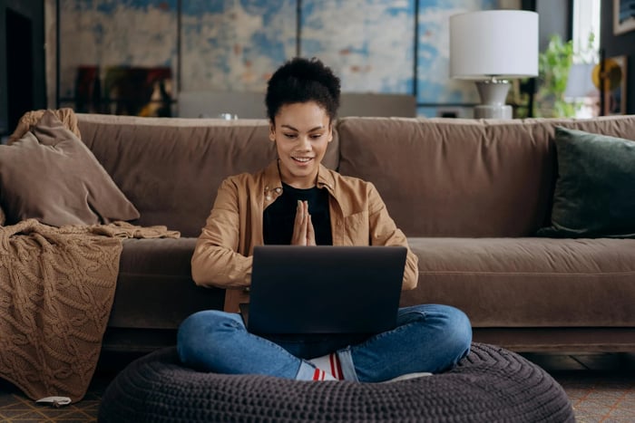 Étudiante souriante avec son ordinateur portable, installée dans son logement